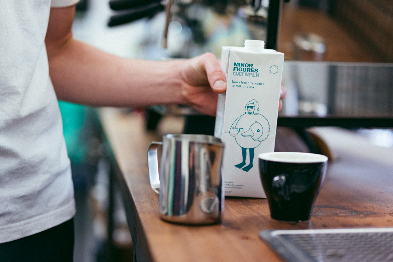Image of barista holding Minor Figures Oat milk whilst making coffee